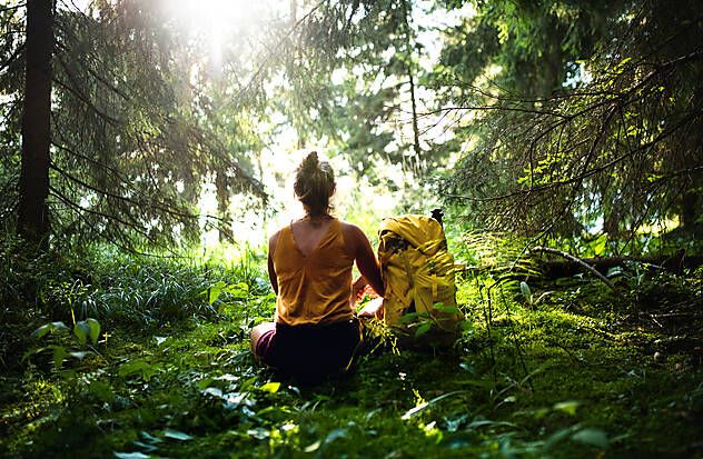 Frau sitz im grünen im Wald mit ihrem Rucksack