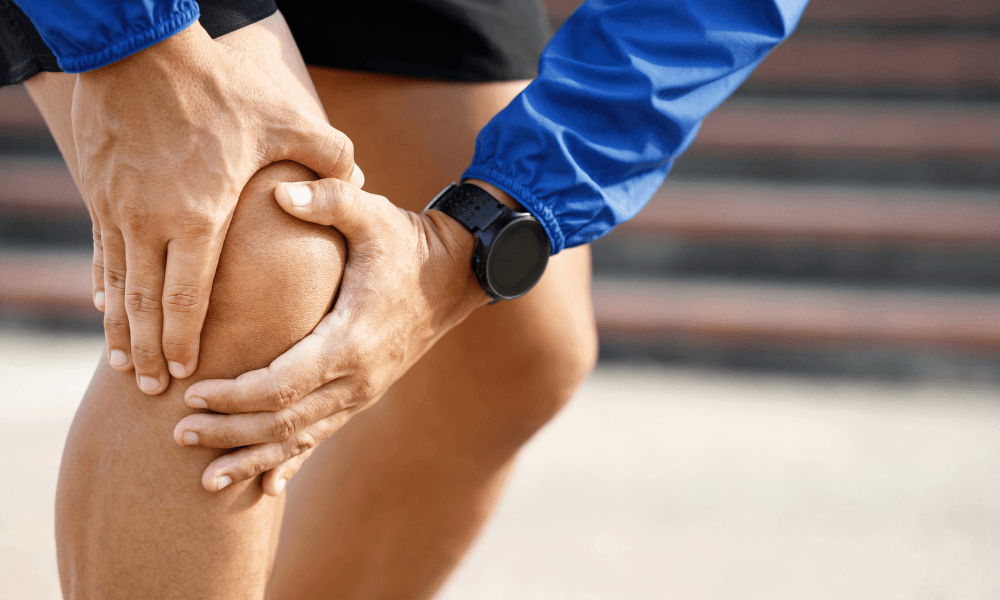 Mann greift sich an das Knie vor Schmerzen
