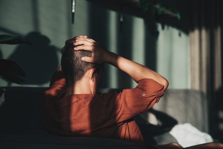 Mann hält sich mit beiden Händen den Kopf fest 